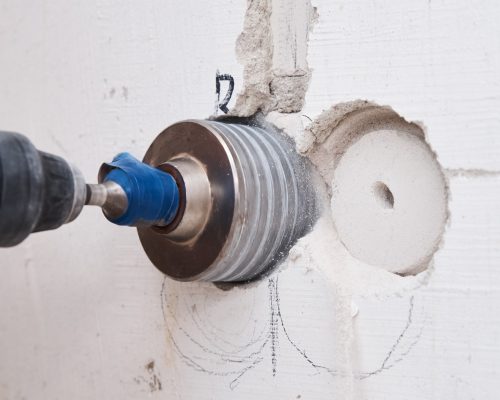 Builder with hummer drill perforator drills hole in a wall